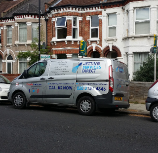 Investigating blocked drain gully at rear of property in Pathfield Road, Streatham Common, South London SW16