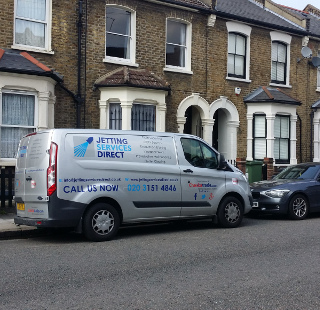 Investigating blocked drain gully at rear of property in Alloa Road, Surrey Quays, South East London SE8